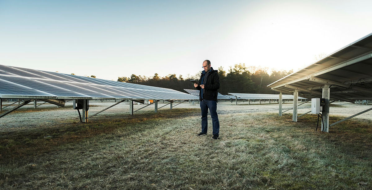 Industrial assembly line with blue bins on a conveyor and workers at stations.